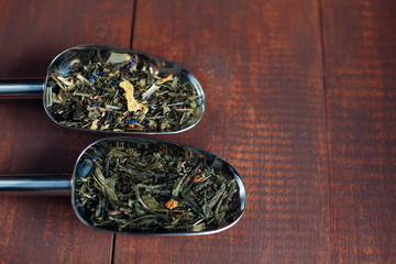 Fototapeta na wymiar assortment of dry tea in spoons, on wooden background
