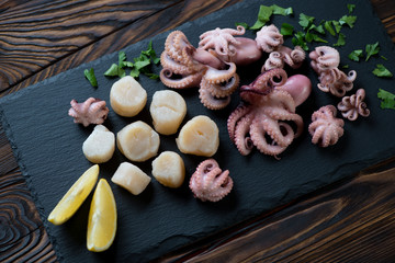 Marinated octopuses and raw sea scallops on a stone slate tray