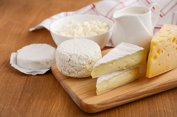 Fresh dairy products. Milk, cheese, brie, camembert and cottage cheese on the wooden background. Horizontal permission. Selective focus. Copy space.