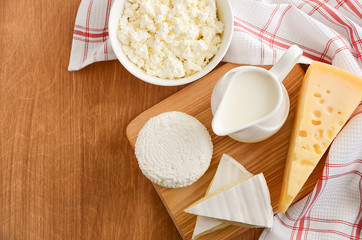 Fresh dairy products. Milk, cheese, brie, camembert and cottage cheese on the wooden background. Horizontal permission. Top view. Copy space.