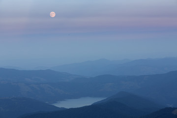 Full moon over mountains and lake