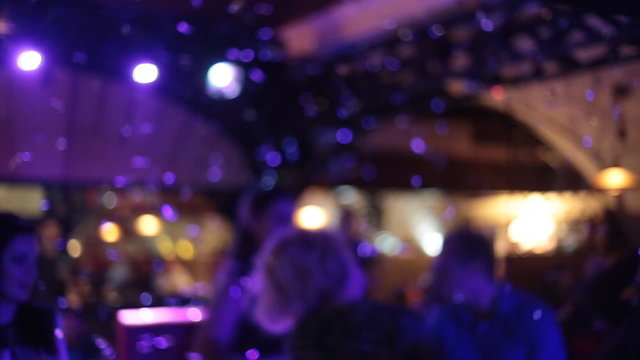 People dance at party in night club with color light, defocused
