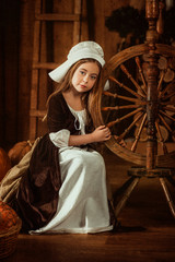little girl in the image of Cinderella sits near a spinning wheel from the hands , hip toning ,...