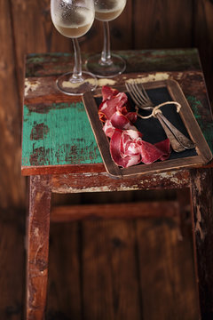 Cured Meat and vintage forks on textured Chalkboard and old wood