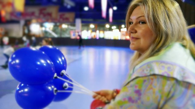 Female with balloons on the roller rink, skating-rink . Teens, children on roller skates, roller skating, romantic active leisure in the entertainment center in the skating-rink. Slow motion