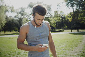 young man with earphones and smartphone at park