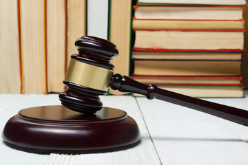 Law book with wooden judges gavel on table in a courtroom or law enforcement office.