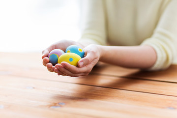 close up of woman hands with colored easter eggs