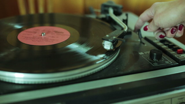 Woman turned on the vinyl player close-up