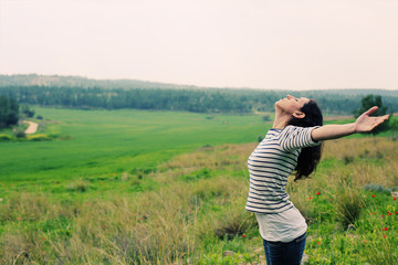 Woman with open arms standing outdoors