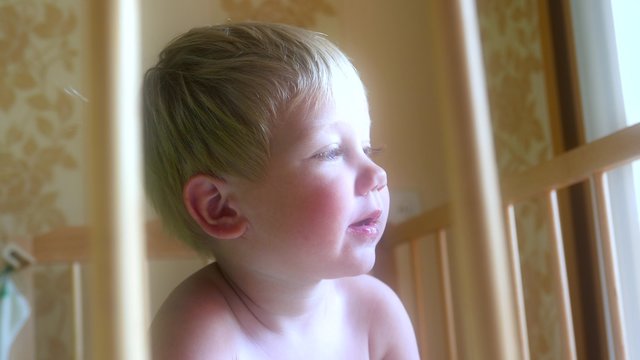 Kid child baby boy is smiling, playing in a cot. Childhood dreams and memories.