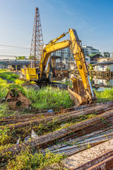 Old backhoe and steel rods at construction site. They are construction equipment and materials.