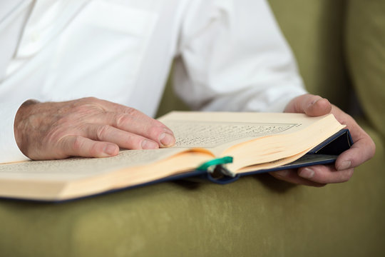 An old man hands holding the Koran. Shallow dof