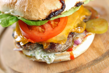Tasty cheese beef burger with lettuce, cheddar, barbecue sauce, tomatoes, pickles and tzatziki