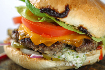 Tasty cheese beef burger with lettuce, cheddar, barbecue sauce, tomatoes, pickles and tzatziki