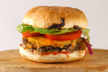 Tasty cheese beef burger with lettuce, cheddar, barbecue sauce, tomatoes, pickles and tzatziki