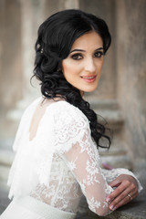 Fototapeta premium Beautiful innocent brunette bride in white dress posing near chu