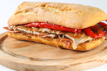 Tasty pork grilled serranito sandwich in a ciabatta with ham and red pepper on a white background - obrazy, fototapety, plakaty