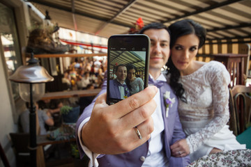 Happy newlywed couple taking a selfie on their phone