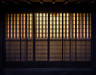 Fototapeta premium Lath wooden wall with background incandescent light. Pattern of vintage wall in Japan.