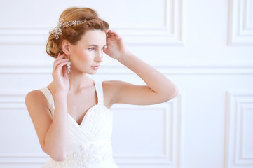 Naklejka na ściany i meble Calm blond bride with blue eyes wearing white gown