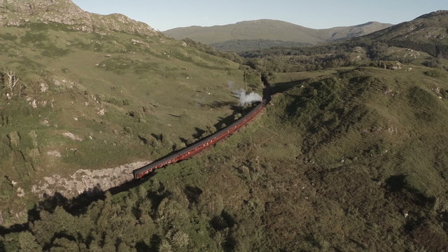 Aerial shot of the Jacobite Steam Train going through stunning scenary in the Scottish highlands 
