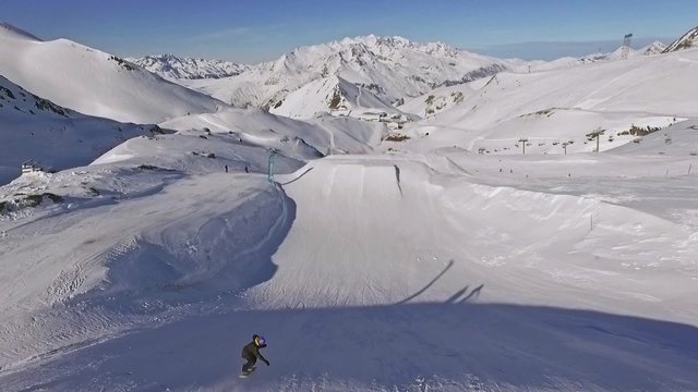 Aerial of a snowboarder jumping in the snowpark. This is a slowmotion video.