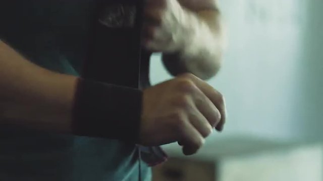 Male weightlifter putting on wrist wraps
