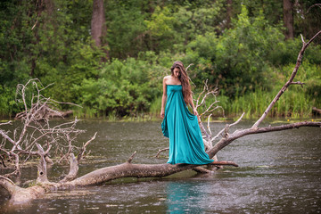 girl wearing dress standing in river near forest