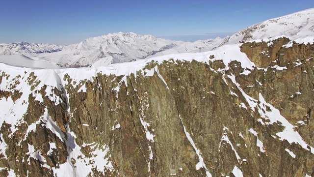 Aerial of a rocky mountain and slopes behind. This is a 4k video.