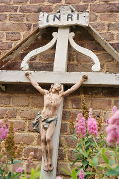 Old weathered Crucifix mounted on a brick wall in a hamlet in the Belgian Ardennes, Wallonia