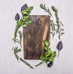 Vintage cutting board with herbs on wooden rustic background top view close up place for text,frame