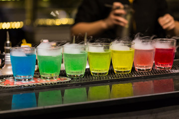 Obraz na płótnie Canvas A group of shot glasses with a rainbow of colored drinks.