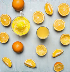 sliced oranges, a juicer, a glass of juice n wooden rustic background top view close up