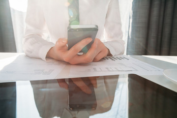 Businesswoman using smart phone in front of a tablet pc