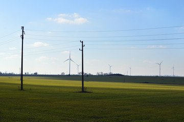 Fototapeta na wymiar Wind generators and electric grid in a green field