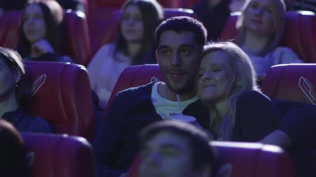 Young romantic couple is watching a film screening in a movie cinema theater. Shop on RED Cinema Camera.