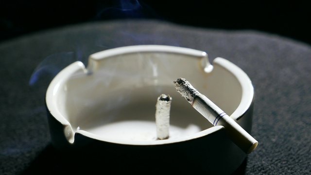 Smoldering cigarette in the ashtray with ash. Smoking tobacco