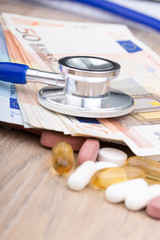 Close up of a stethoscope with some pills and bank notes