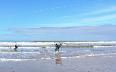 Sidi  Kaouki, Morocco -  January 7, 2016:  two surfers carrying a surfboard on the beach near Essaouira