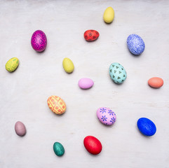 colored decorative easter eggs on a white wooden background top view close up