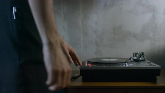 4K cinemagraph - motion photo seamless loop - young adult Caucasian male playing vinyl record on a vintage record player