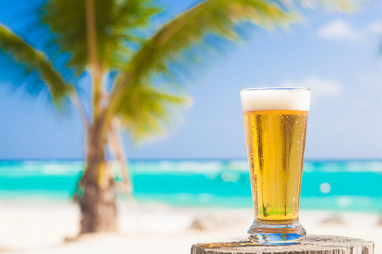 glass of cool beer on table near beach