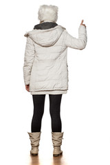 back view of young beautiful woman in winter clothes showing thumbs up
