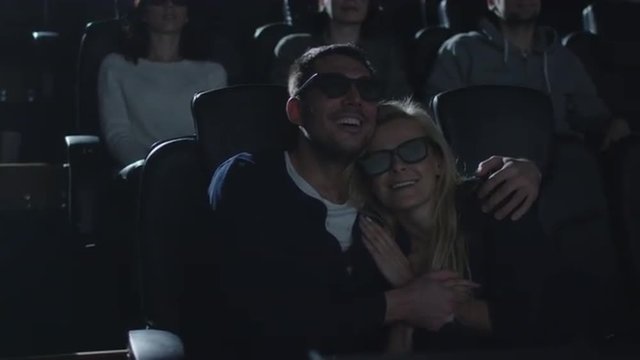 Couple embrace each other while having fun watching 5d film screening in cinema.  Shot on RED Cinema Camera.
