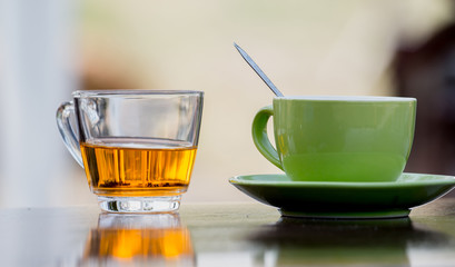 Tea glasses and green ceramic coffee mug on a wooden table.