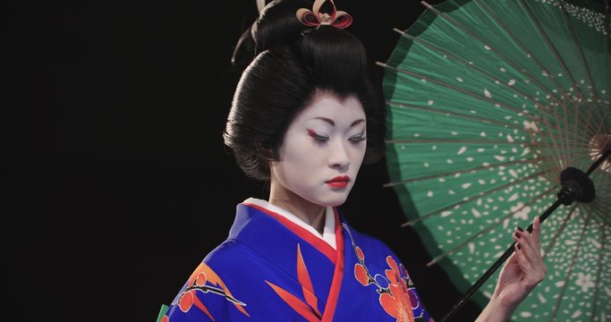 4K beautiful Japanese geisha dancing on stage and posing for the camera with an umbrella, in slow motion