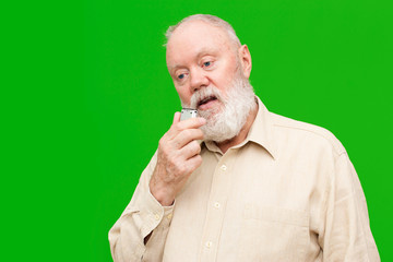 Elderly man is speaking to voice recorder on green background, color and contrast manipulated