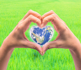 World in heart shape with over women human hands on blurred natu