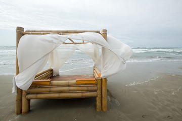 lit en bambou avec des voiles blanches sur la plage